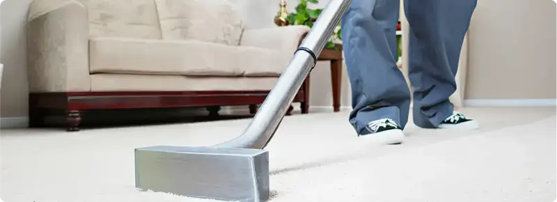 Carpet cleaning technician using a hot-water extraction wand on a light-colored carpet in a living room, Duluth, MN.