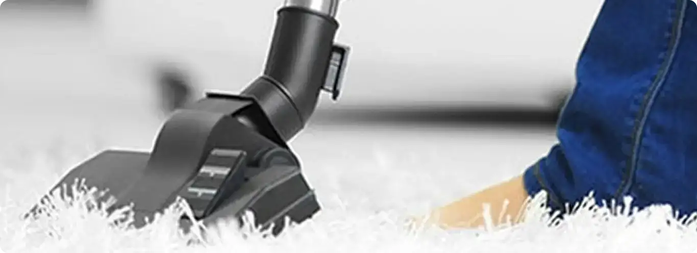 Close-up of a professional vacuuming a white carpet in Adolph.
