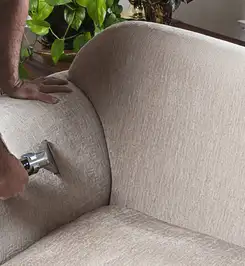 Professional upholstery cleaner deep-cleaning a fabric sofa with a handheld extraction tool and hose Duluth, MN.